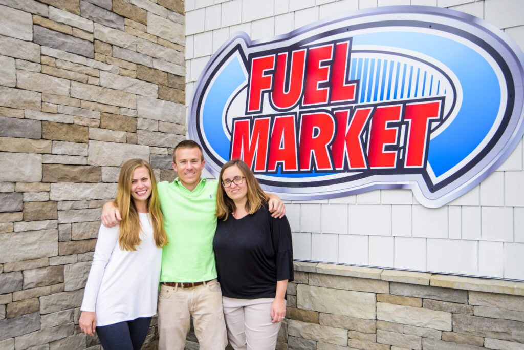 three people and Fisher Fuel Market banner